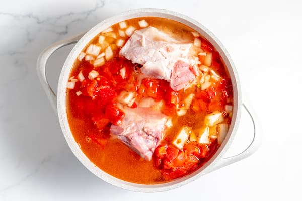 Image, taken from above shows soup ingredients together in a pot ready to boil.