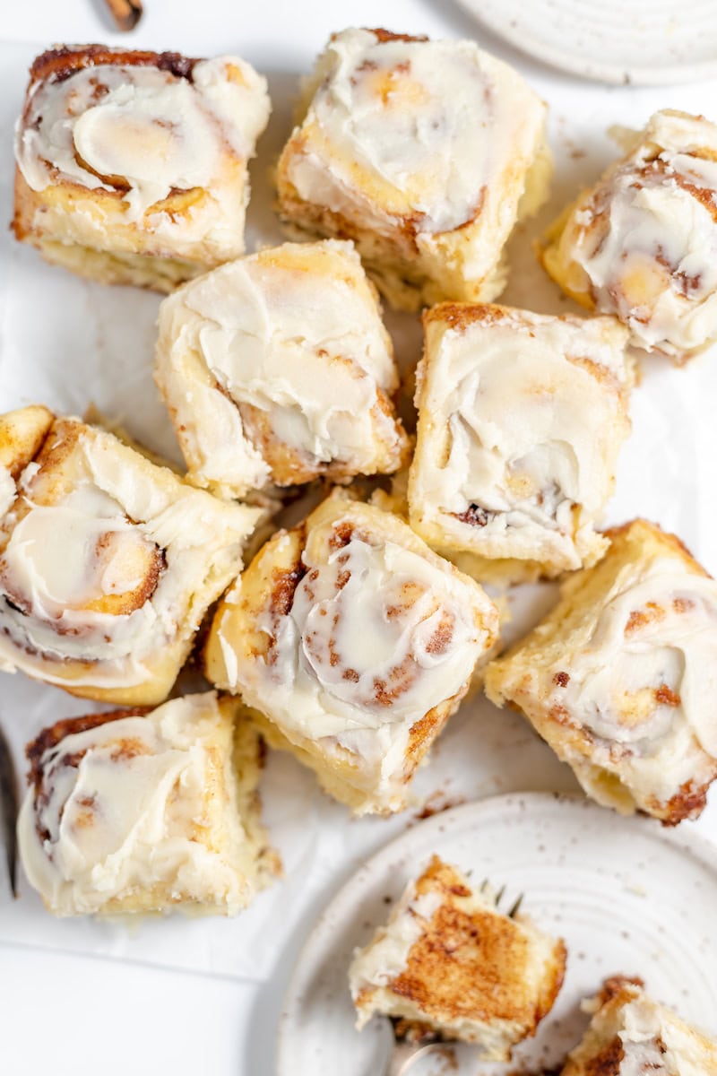 Image, taken from above, shows sourdough cinnamon rolls with icing cut apart and laying on a table.