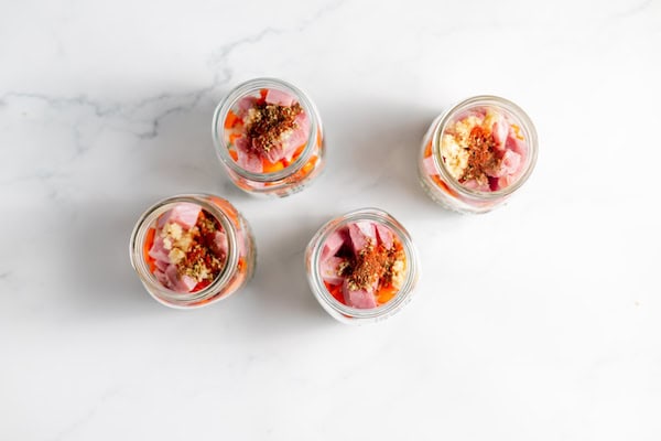 Image, taken from above shows ham and seasonings added to the split pea soup jars.