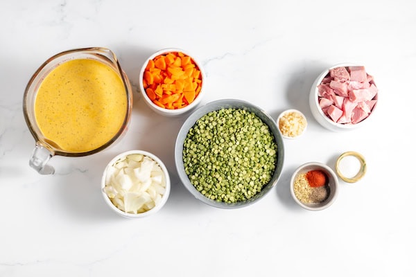Image, taken from above shows bowls of ingredients to make split pea soup on a table