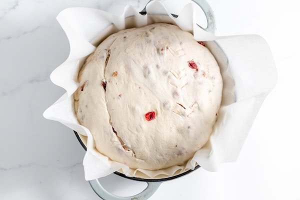 scored loaf of cranberry walnut bread in hot pan