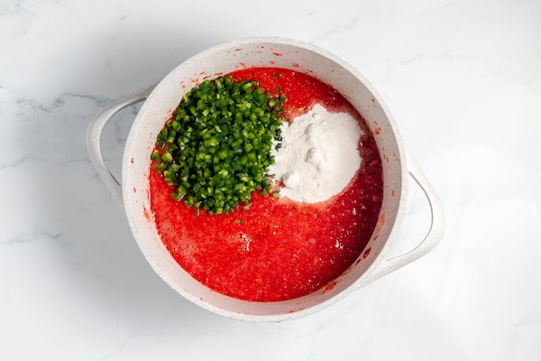 ingredients for making jalapeno strawberry jam in a large pan
