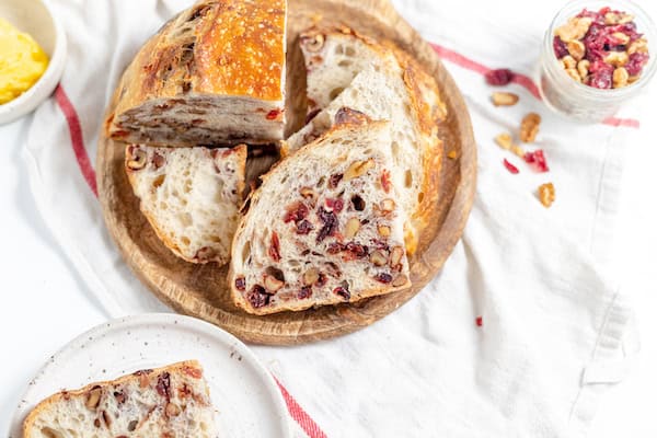 sliced cranberry walnut bread on a cutting board with butter