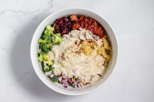 dressing drizzled over broccoli pasta salad