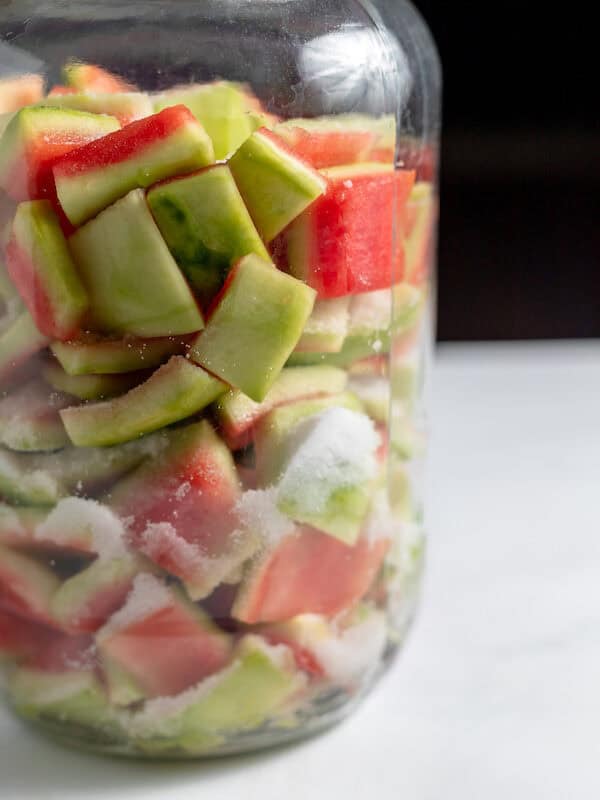 watermelon rind layered with salt in a jar
