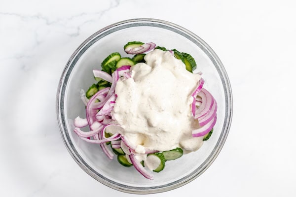 creamy dressing drizzled over cucumber and onion