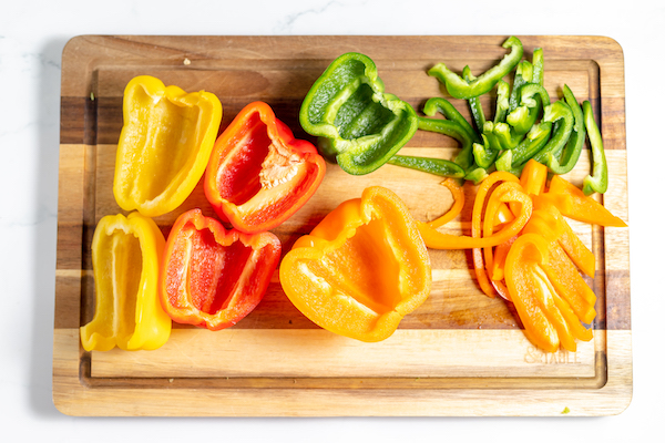 bell peppers on a cutting board being cut into strips